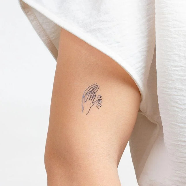 Zartes schwarzes temporärtattoo von zwei händen die sich halten mit dem wort love aus secret play kinky collection