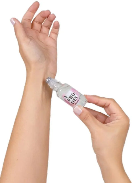 Ein klarer glas-rollerflakon mit rosa-weißem label aero dis wird auf das innere handgelenk gerollt secretplay afrodis parfümöl mit pheromonen für frauen 20 ml