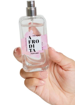 Ein klarer glasparfumflakon mit silbernem sprühkopf und rosa etikett afro di ta parfum für frauen