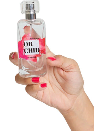 Eine klare glasparfümflasche mit silberner sprühdüse und pinkem blumenetikett or chid secretplay orchidée natürliche pheromon parfumspray 50 ml
