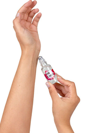 Eine klare glas-roll-on-flasche mit einem rosa-weißen etikett or chic wird von händen gehalten für secretplay orchideen-parfümöl mit natürlichen pheromonen 20 ml