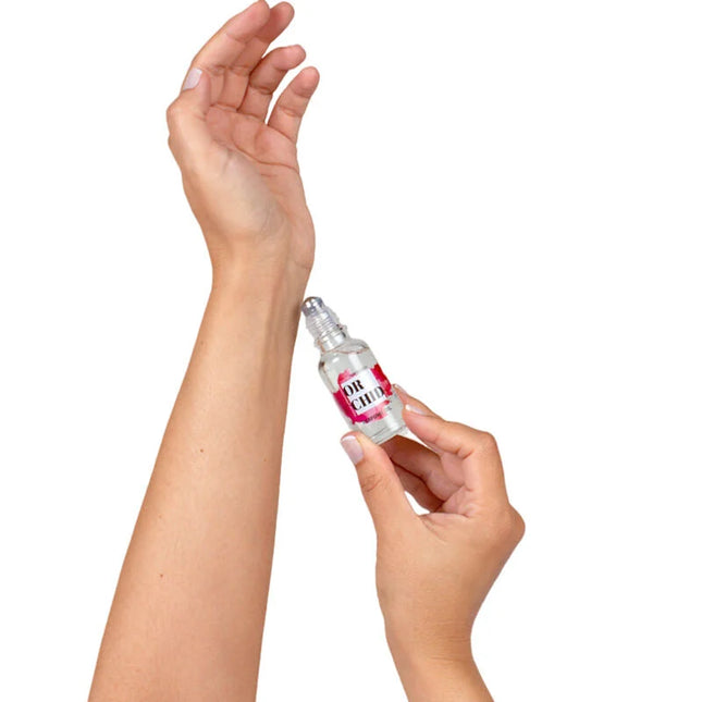 Eine klare glas-roll-on-flasche mit einem rosa-weißen etikett or chic wird von händen gehalten für secretplay orchideen-parfümöl mit natürlichen pheromonen 20 ml