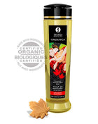 Goldgelbes bio massageöl shunga in schlanker transparenter flasche mit schwarzem verschluss und etikett mit paar vor roten ahornblättern