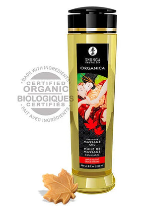 Goldgelbes bio massageöl shunga in schlanker transparenter flasche mit schwarzem verschluss und etikett mit paar vor roten ahornblättern