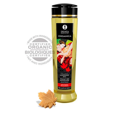 Goldgelbes bio massageöl shunga in schlanker transparenter flasche mit schwarzem verschluss und etikett mit paar vor roten ahornblättern