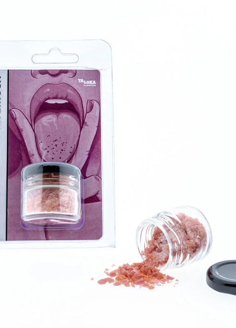 Ein klarer glasbehälter mit schwarzem deckel, der rosa-rote körnige erdbeer-zauberküsse von taloka enthält