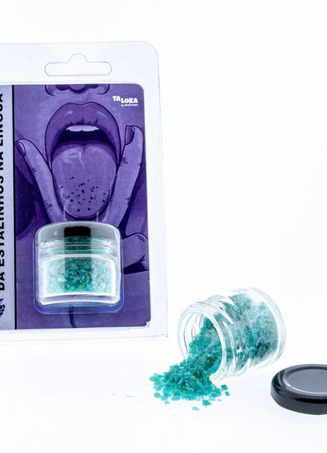 Ein kleines klares glas mit schwarzem deckel gefüllt mit leuchtend türkisfarbenen kristallinen flocken von taloka prickelnd für die zunge magische küsse der blauen himbeere