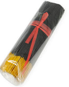 Schwarze und gelbe räucherstäbchen mit exotischen mango-pheromonen in klarem plastik mit rotem band gebündelt