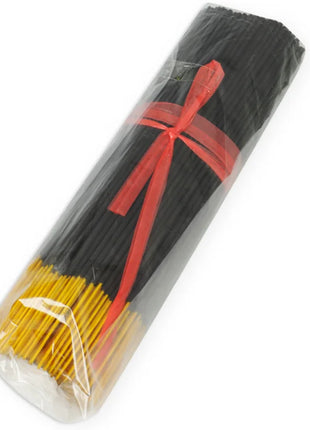 Schwarze und gelbe räucherstäbchen mit exotischen mango-pheromonen in klarem plastik mit rotem band gebündelt