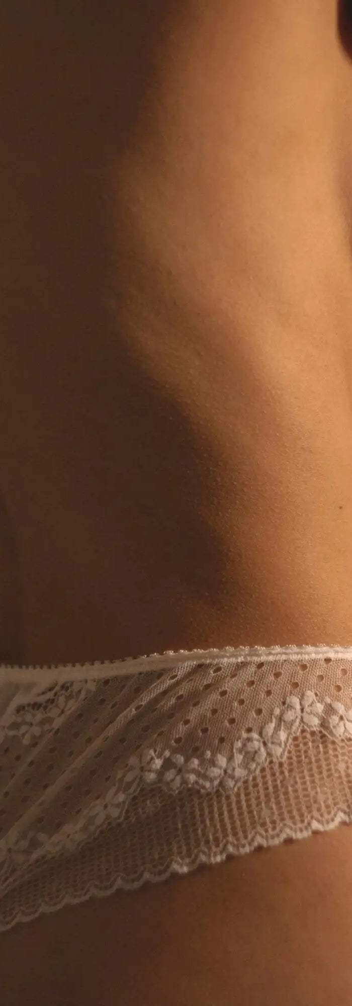 Weiße Spitzenunterwäsche mit zarten Blumenmustern und gewellten Rändern.